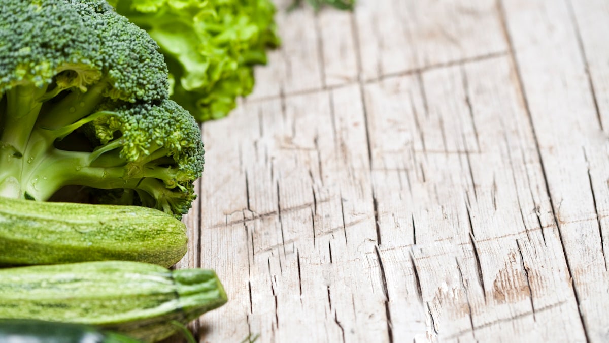 Broccoli and cucumbers are lined up on a table